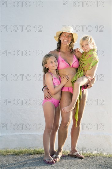 Caucasian mother and daughters smiling on beach