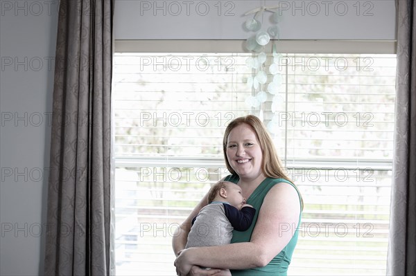 Mother holding baby son at window