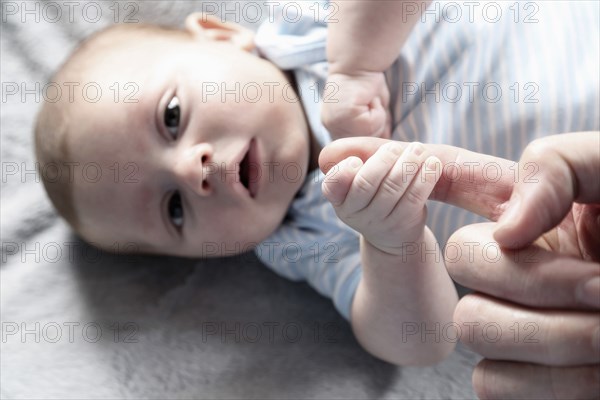 Close up of baby boy playing with fingers of father