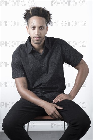 Serious Mixed Race man sitting on chair