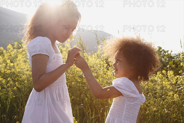 Mixed race girls smelling flowers