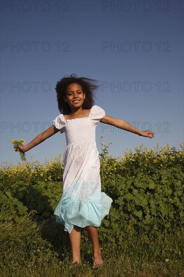 Mixed race girl holding flowers in field