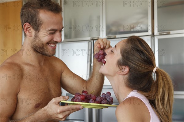 Caucasian man feeding wife grapes