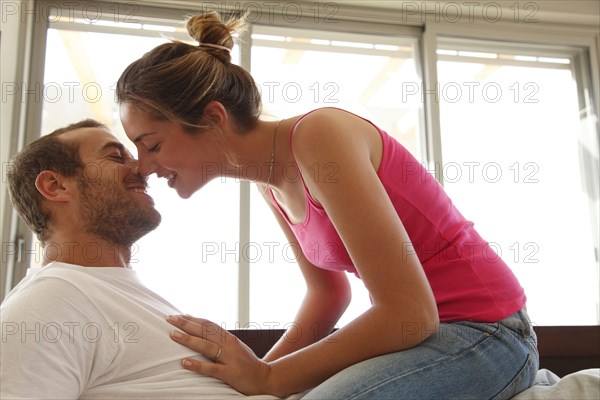 Caucasian woman sitting on husband's lap kissing him