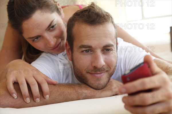 Caucasian woman watching husband using cell phone