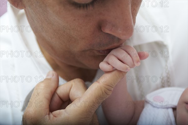 Hispanic father kissing baby daughter's hand