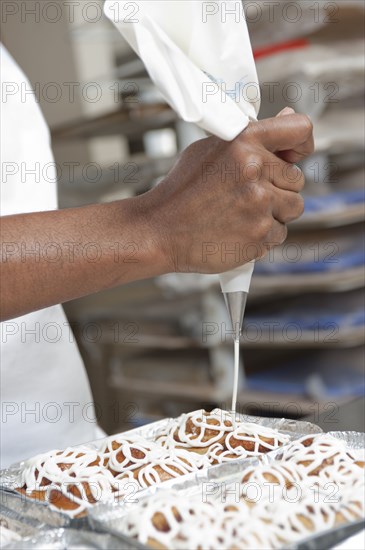 Mixed race baker icing pastry in commercial kitchen