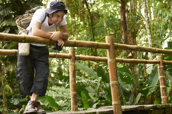 Hispanic man with backpack standing on wooden walkway