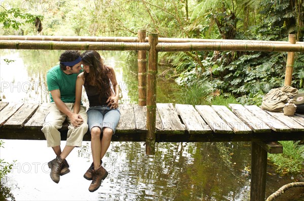 Hispanic couple sitting holding hands on wooden walkway