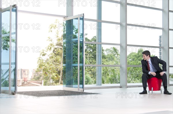 Hispanic businessman sitting on bench in lobby