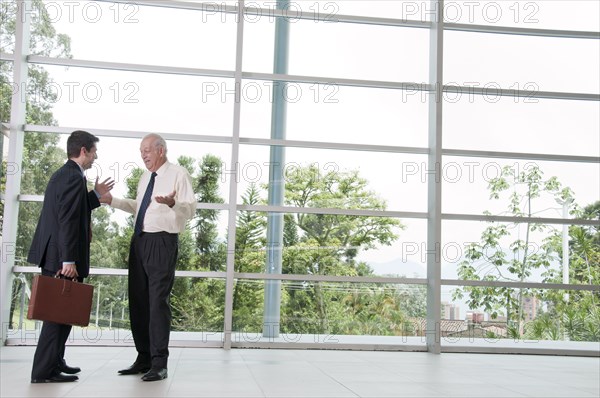 Hispanic businessmen talking together in lobby