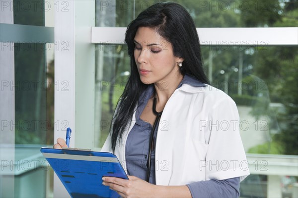 Hispanic doctor writing in medical chart