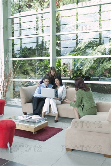 Hispanic business people sitting on sofas working together