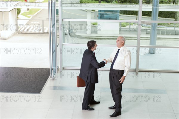 Hispanic businessmen shaking hands in lobby