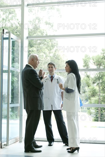 Hispanic business people talking to doctor in lobby