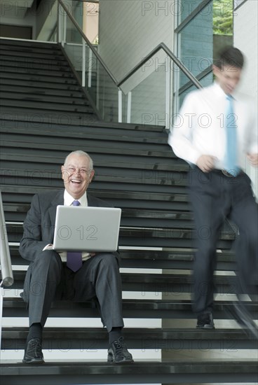 Hispanic businessman using laptop on staircase