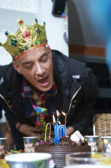 Hispanic man blowing out candles on birthday cake