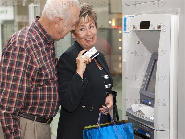 Senior Hispanic couple withdrawing money from ATM