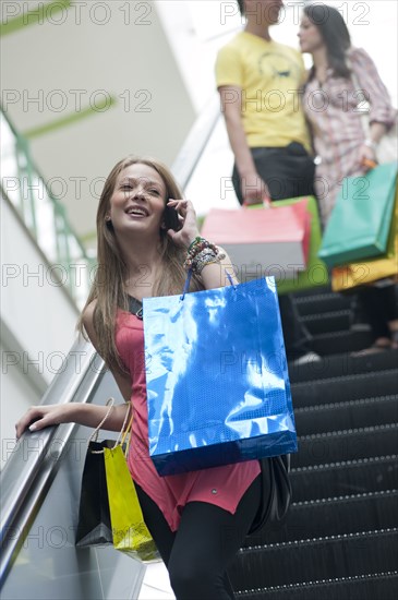 Hispanic woman on escalator talking on cell phone