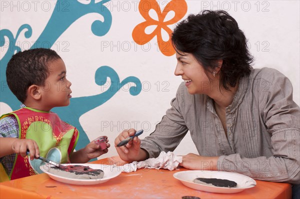 Hispanic mother painting with son