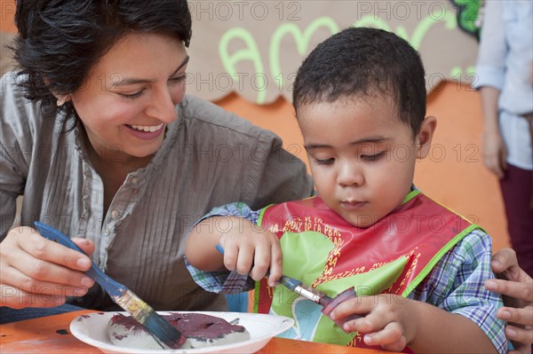 Hispanic mother painting with son