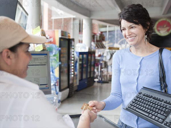 Hispanic woman paying with credit card in store