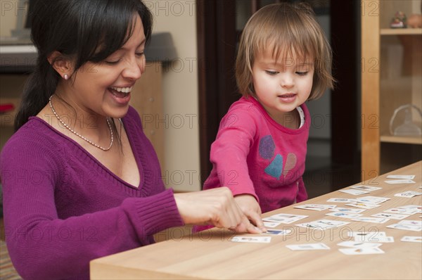 Hispanic mother and daughter playing card game