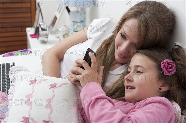 Hispanic mother and daughter looking at cell phone