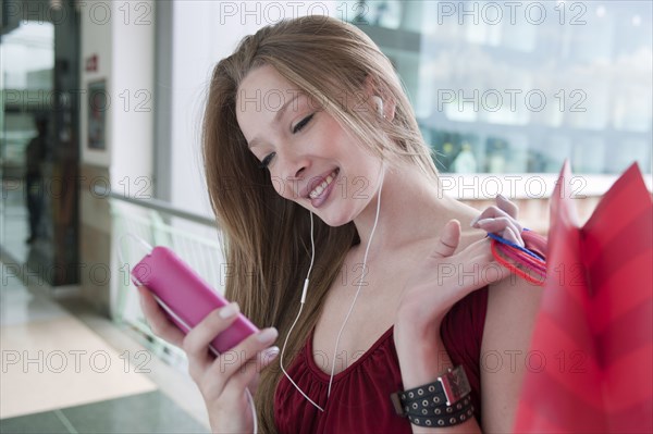 Hispanic woman carrying shopping bags listening to mp3 player