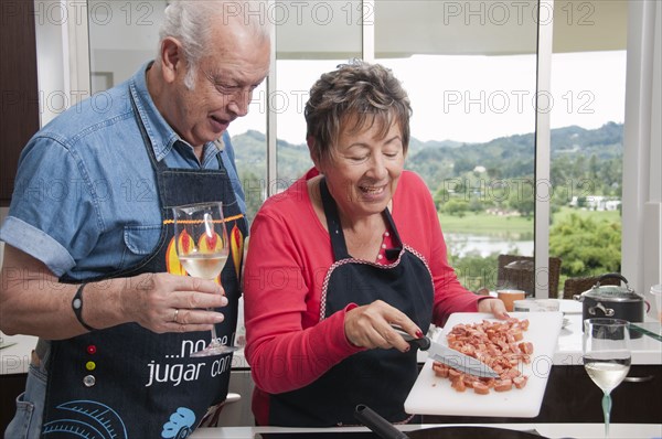 Senior Hispanic couple cooking together in kitchen