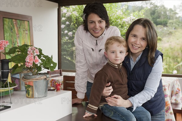 Hispanic women hugging boy on porch