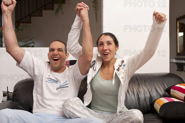 Hispanic couple cheering and watching television