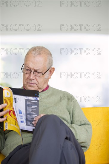 Senior Hispanic man reading magazine