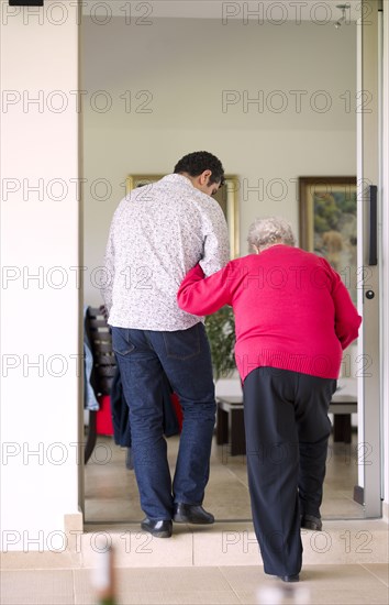 Hispanic man helping his grandmother to walk