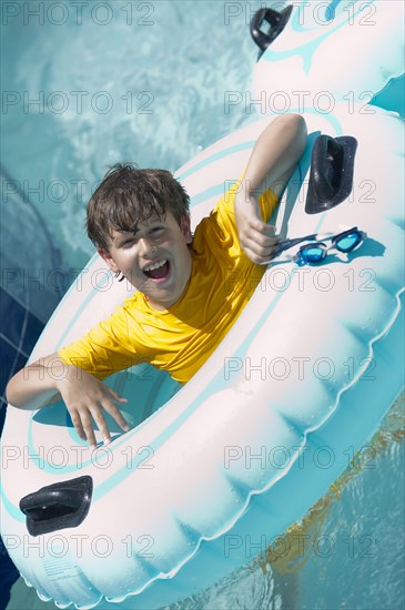 Hispanic boy floating on raft in swimming pool