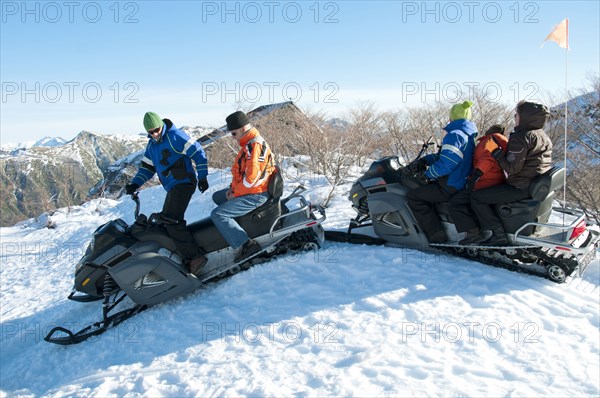 Hispanic family riding on snowmobiles through snow