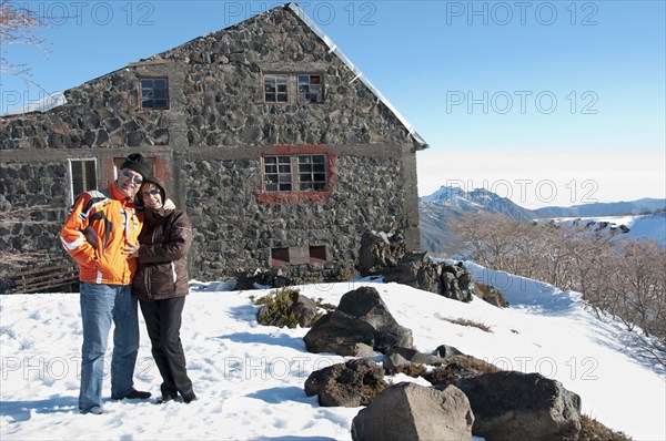 Hispanic couple standing in snow near house