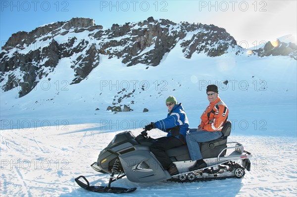 Hispanic men riding snowmobile together