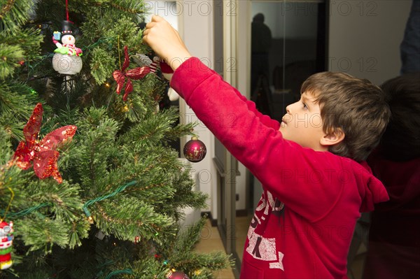 Hispanic boy decorating Christmas tree