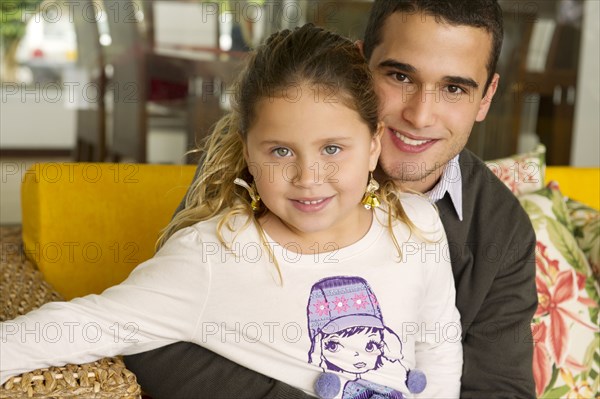 Hispanic girl sitting on father's lap