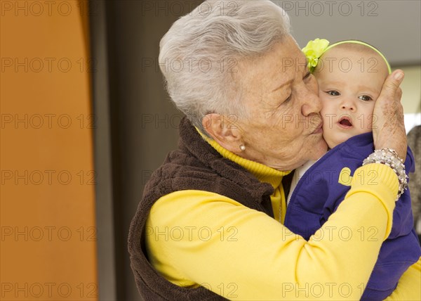 Hispanic grandmother kissing baby granddaughter