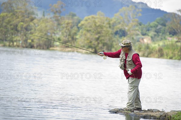 Hispanic man fishing in lake