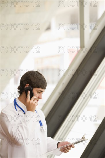 Hispanic doctor holding clipboard and talking on cell phone