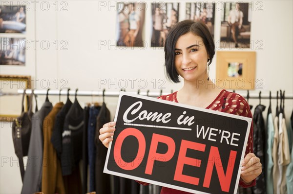 Hispanic woman holding open sign