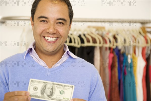 Hispanic man holding cash in clothing store