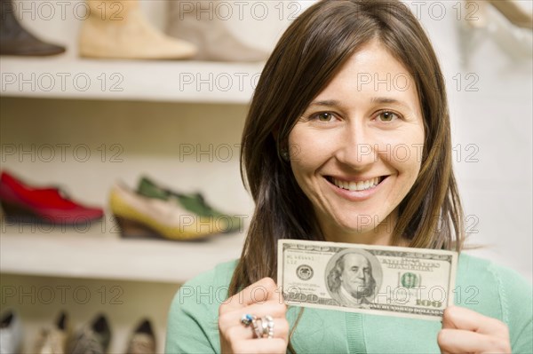 Hispanic woman holding cash in shoe store