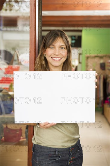 Hispanic woman holding blank sign in store