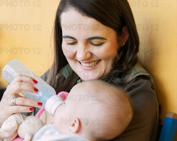 Hispanic mother feeding baby daughter