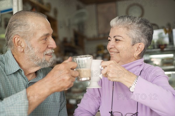 Hispanic couple toasting with coffee cups in cafe