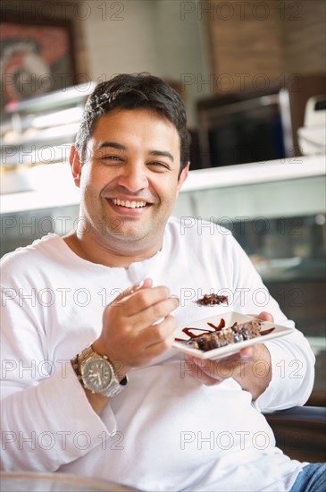 Hispanic man eating dessert in cafe